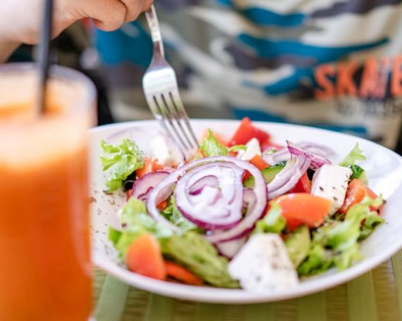 Colorful salad with fresh vegetables and a refreshing drink on a table.