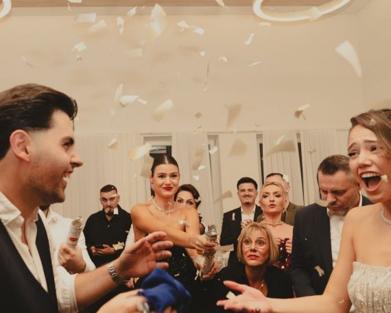 Bride and groom celebrating at a lively indoor wedding reception with friends and family.